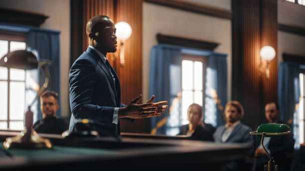 Court of Justice and Law Trial: Male Public Defender Presenting Case, Making Passionate Speech to Judge, Jury. African American Attorney Lawyer Protecting Client's Innocents with Supporting Argument.